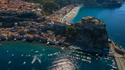 Fototapeta premium Aerial view of the town of Scilla, in the province of Reggio Calabria, Italy. The historic center and the hamlet of Chianalea are in the foreground. The town beach is in the background.