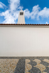 Minimal white wall with chimney, red tile roof and bright blue sky