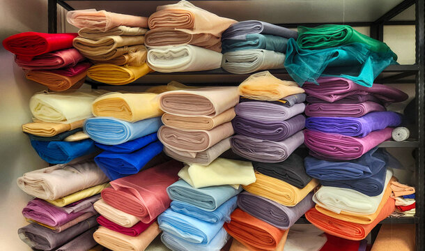 rolls of fabric in various colors, patterns, and types lined up on shelves