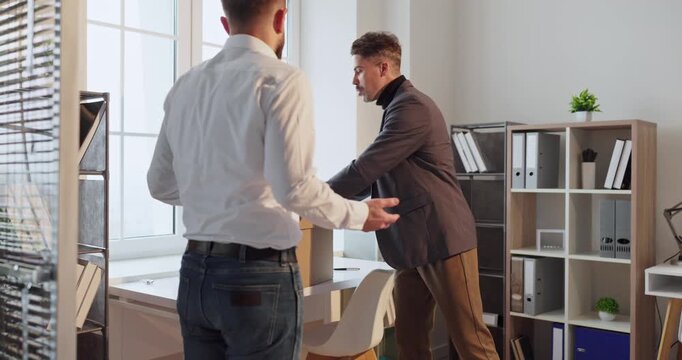 Manager and employee in office dismissal conflict. Belongings go into a box as a layoff meeting sparks serious argument and decisions. Strong concept of workplace stress and job termination.