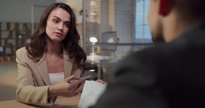 Agent and client signing contract in office. Advisor presents documents and explains terms at desk, highlighting options and responsibilities. Clear agreement and trusted partnership concept.