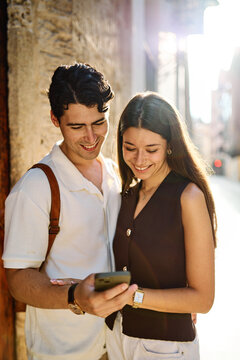 Couple enjoys a sunny day walking together in a charming urban area during late afternoon or tourists visiting a destination  looking at phone map app