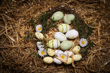 Obraz premium Traditional Easter eggs with floral patterns and stripes lying in a rustic straw nest