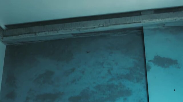 Abstract grungy wall surface featuring a small rectangular intercom button and thin wire, displaying an aged, minimalist aesthetic with pale blue green tones and subtle imperfections