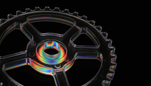 Photoelasticity stress analysis of transparent gear showing rainbow polarized light patterns