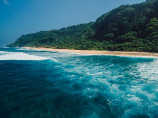 Drone view of beach coastline with green hills in Bali. Nyang Nyang beach