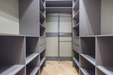 Spacious dressing room with spacious gray cabinets and shelves. Coat hanger.