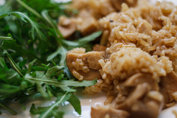 Mushroom risotto or rice pilaf served with fresh green arugula salad on plate. Vegetarian dinner meal.