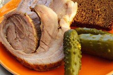 Close up of sliced roasted pork meat roll with pickles and rye bread. Appetizing homemade cold cut dish.