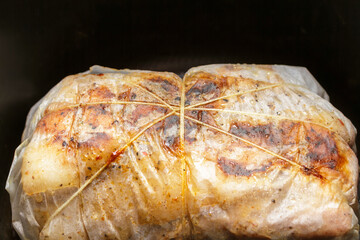 Baking meat roll wrapped in parchment paper inside oven or multicooker. Cooking process close up.