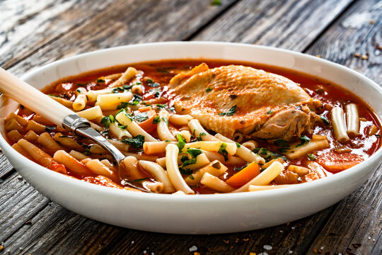 Tomato soup with chicken thigh and noodles on wooden table	
