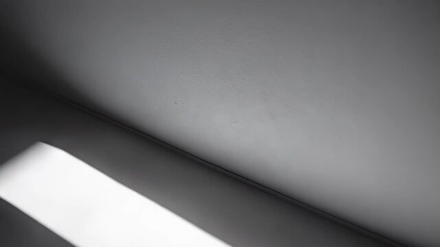 Abstract artwork featuring strong contrasting lines of natural sunlight and dark shadows on a textured wall, forming a compelling geometric composition, emphasizing space and design