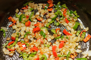 Close up texture of sauteed onions and peppers cooking in oil. Vegetable base for soup or stew preparation.