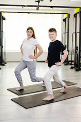 Fototapeta premium Trainer and youth doing lunges in gym