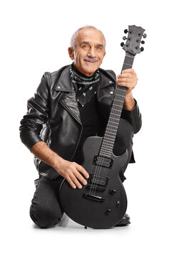 Snior man in a black leather jacker kneeling with an electric guitar