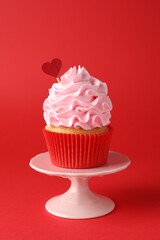 Happy Valentine's Day. Tasty cupcake with heart topper on red background, closeup