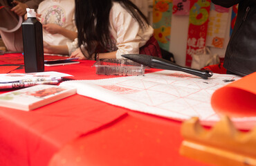 Close up of woman writing Happy New Year with Chinese calligraphy on couplets for celebration. Chinese calligraphy workshop - create traditional festive symbols and Chinese characters
