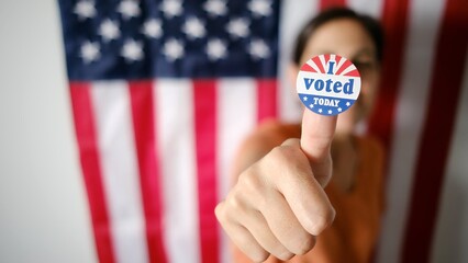 Young woman proudly displaying an i voted today sticker on her thumb, promoting active...