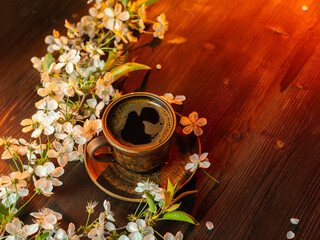 cup of coffee with spring flowers on a wooden table, sunny bright light