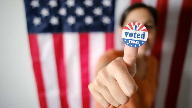 Young woman proudly displaying an i voted today sticker on her thumb, promoting active participation in the election process and upholding democratic values