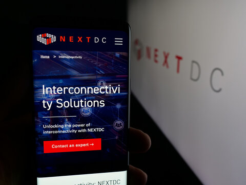 Stuttgart, Germany - 01-21-2026: Person holding smartphone with web page of Australian data center company NextDC Ltd. on screen in front of logo. Focus on center of phone display.