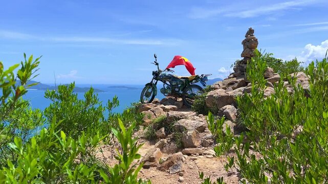 Nha Trang, September 9, 2025: View from the observation deck on the seashore. Top view of the bay, city, islands, sandy beach, and Vinpearl. Motorcycle with the Vietnamese flag on the Angel Mountain. 