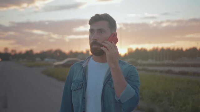 Man seeks roadside help, Driver gesturing animatedly while negotiating roadside assistance during sunset