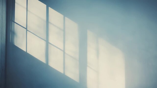 Sunlight streams into a minimalist empty room, creating strong geometric grid window shadows on the light colored wall and reflecting on the polished concrete floor, providing clean background space