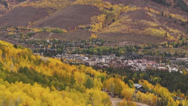 Town of Vail revealed with mountains and fall colored forest, drone video, Colorado 4K