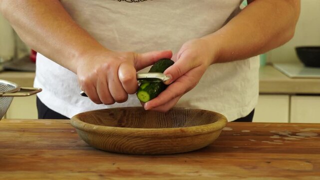 Woman cutting fresh cucumber for salad
