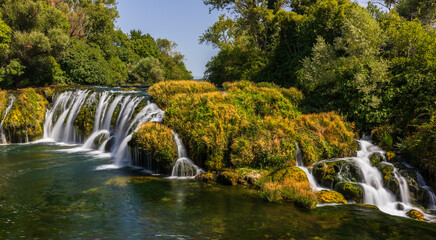 Obraz premium Kocusa waterfall flowing through vegetation in Bosnia and Herzegovina.