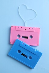 Obraz premium Music cassettes and heart made with tape on light blue background, top view