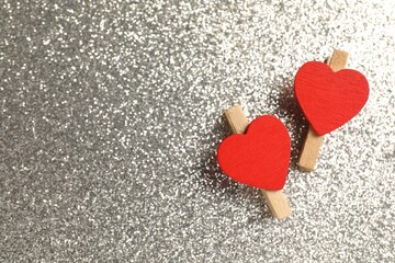 Fototapeta premium Love. Clothespins with red decorative hearts on shiny gray background, flat lay. Space for text