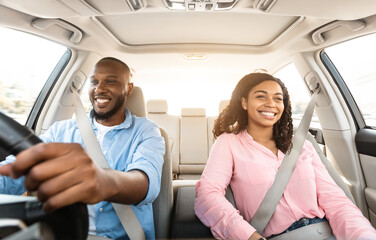 Front view portrait of smiling handsome African American man driving modern luxury car, happy...