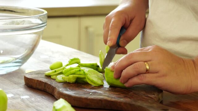 Woman cutting fresh cucumber for salad
