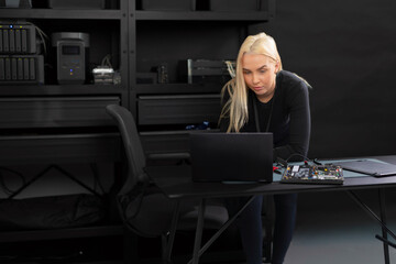 Female IT technician in a server room working on a laptop and diagnosing hardware