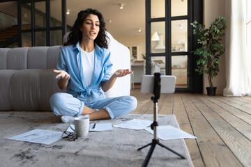 Young female teacher giving online lesson on smartphone camera, blogger filming video content for...