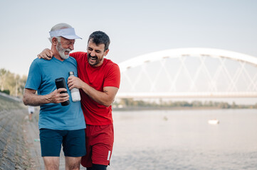 Father and son laughing together after exercising by the river
