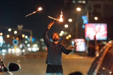 Street performer juggling flaming clubs at night