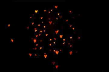 Valentine's Day - a bokeh of red hearts, a sign of love, on a black background. Graphic resource for advertising design.