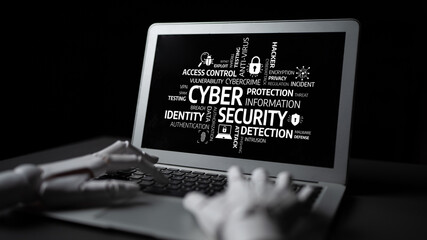 A robotic hand hovers over a laptop displaying keywords associated with cyber security. This image...