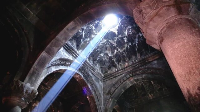 Dramatic sunbeam entering the stone interior of Geghard Monastery in Armenia highlighting ancient architecture spirituality and cultural heritage