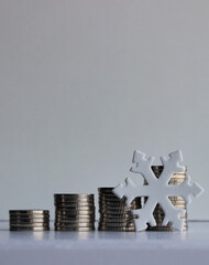  A symbol of cold in front of neatly stacked coins demonstrating declining profits. A stock photo on the topic of finance and economics during a crisis