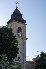 Obraz premium Stone Bell Tower Rising Over Lush Trees Along Quiet Street, Church of Saint Spyridon in Peroj, Istria