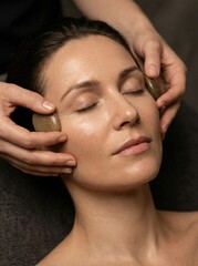 Obraz premium A woman relaxing with stones placed on her face during a soothing massage session.