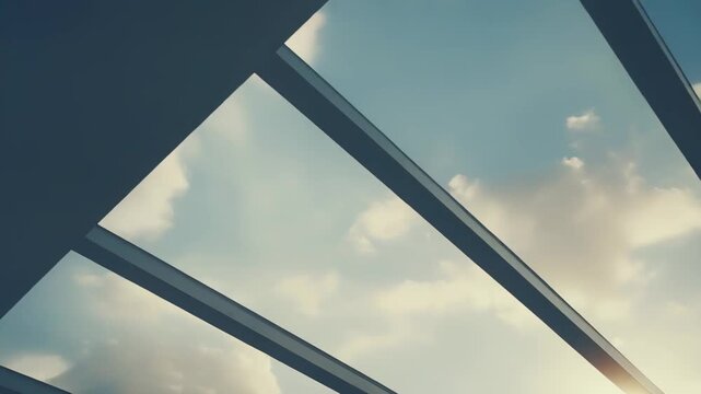 Modern architecture framing a bright cloudy sky with warm sunlight streaming through the clear glass roof pane, creating a dynamic perspective and feeling of openness