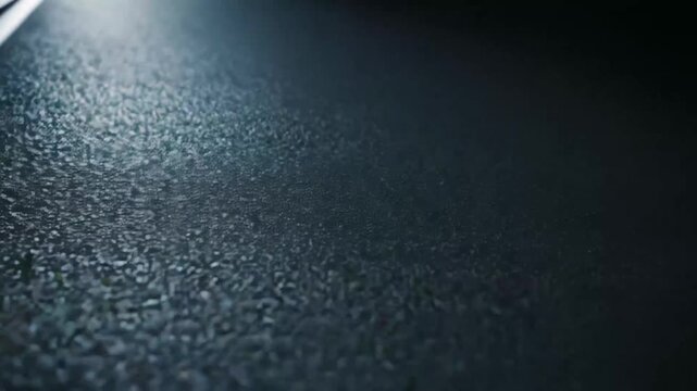 Light beams penetrate a dark space, casting strong, defined shadows and illuminating a textured, slightly reflective ground, suggesting mystery and dramatic contrast