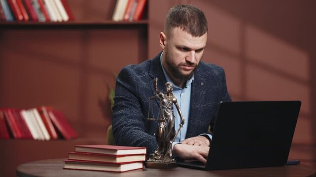 Law and justice concept with male lawyer at desk, laptop, Lady Justice statue and law books. Professional legal practice and modern attorney workspace.