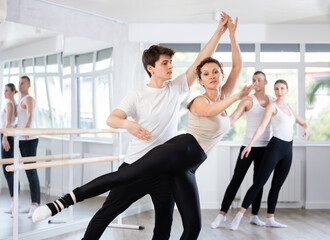 Fototapeta premium Young guy and adult woman perform paired ballet dance in studio