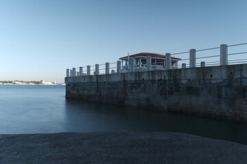 Seaside pier with pavilion over calm water under clear blue sky
